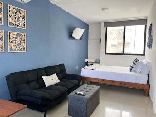 Studio interior with double bed, sofa and wall A/C