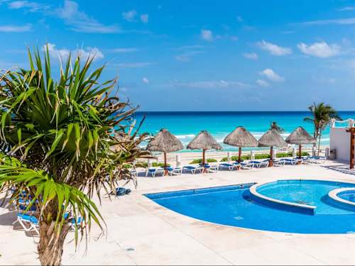 Palm-fringed resort pool with shaded palapas, unwind poolside in the heart of the Hotel Zone