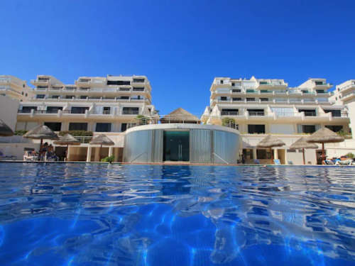 Striking resort building wrapped around a glassy pool, an inviting oceanfront home base in Cancun