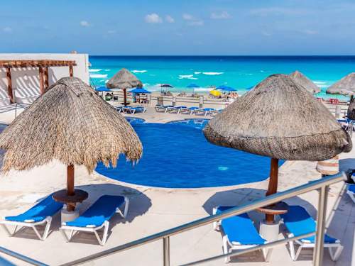 Beachfront pool with loungers and palapas above turquoise water, sun and sea within easy reach