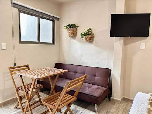 Studio living area with sofa, dining table and Smart TV.
