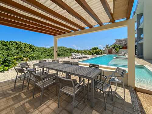 Shaded poolside dining under a wooden pergola, the perfect spot for long island lunches with the sea in view