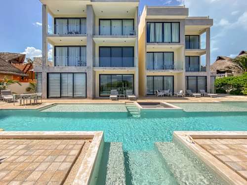 Modern white villa facade wrapped around a glittering pool, your calm island retreat on Isla Mujeres