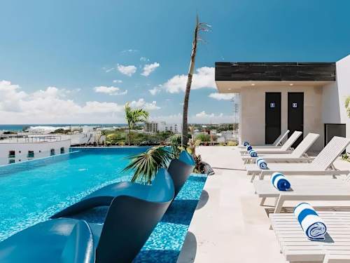 Rooftop infinity pool with loungers and sweeping Caribbean views, your daily escape above Playa del Carmen