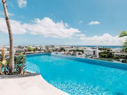 Rooftop pool with swaying palms and open views over Playa del Carmen