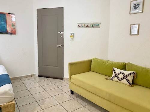 Bright living space with a cheerful green sofa and easy-care tile floors, room to relax after a day out