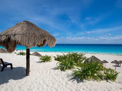 Postcard Cancun beach with a thatched palapa and turquoise water, the Caribbean coast a short ride away