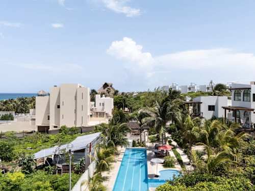 Aerial view of the Isla Mujeres villa complex wrapped in tropical greenery around a long resort pool, your island hideaway from above