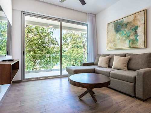 Open living room with a comfy sofa and round coffee table by the balcony, easy indoor living