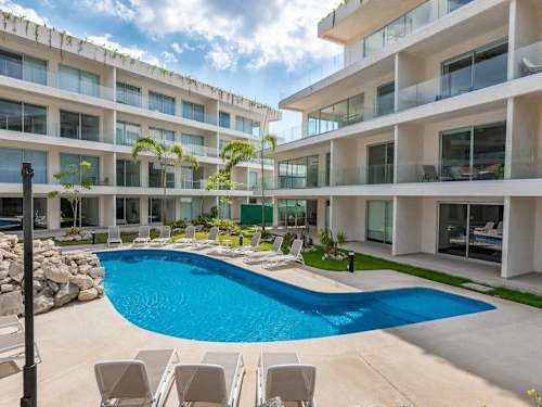 Modern resort facade beside the curving pool, low rise buildings framed by palms