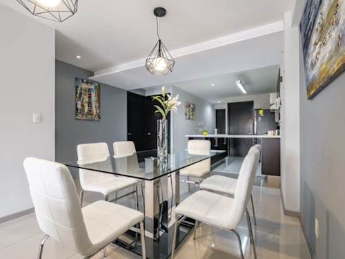 Open dining area with a glass table and the kitchen just beyond, effortless entertaining in Polanco
