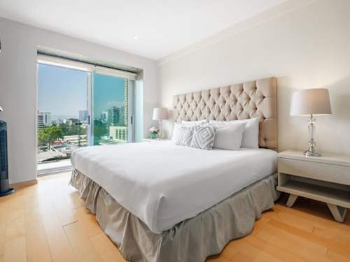 Restful king bedroom with a tufted headboard and skyline window, a serene retreat in the heart of Polanco