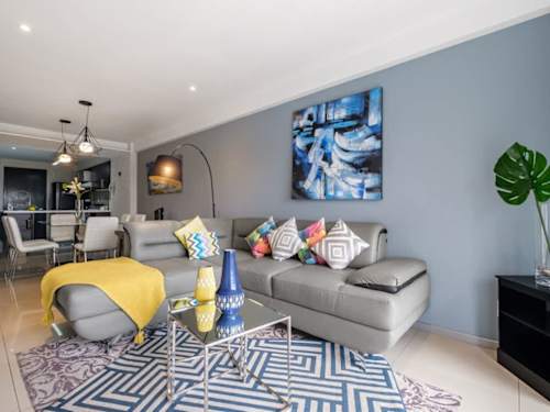 Bright living room with a plush sofa, cheerful accents and floor-to-ceiling city views, easy upscale living