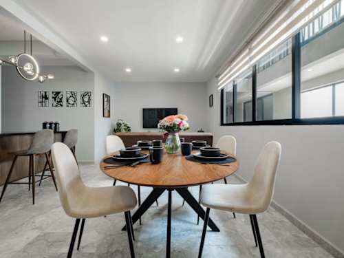 Sunny dining nook with a round wood table for four, perfect for a leisurely Roma Norte breakfast