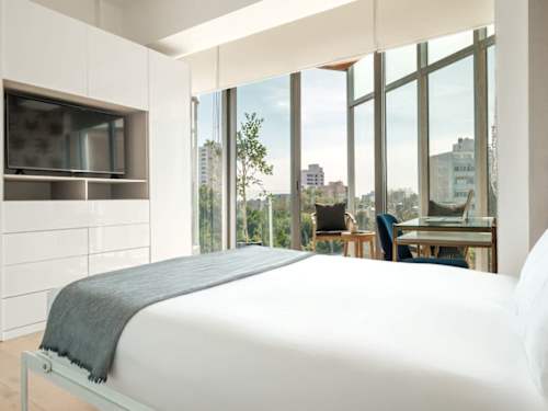 Restful bedroom with a plush bed and floor-to-ceiling skyline windows for a great night's sleep