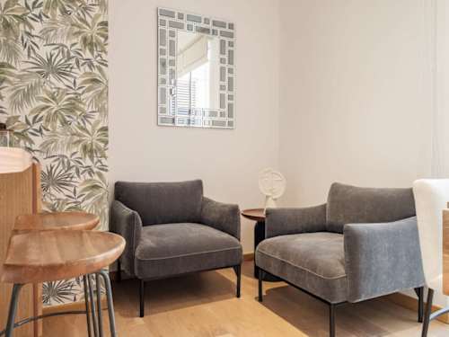 Cozy living area with plush armchairs and botanical walls, easy indoor lounging with character
