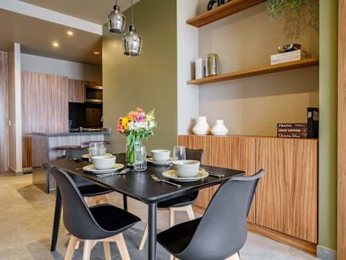 Stylish dining table beside a warm wood kitchen, gather over meals with fresh flowers on the table