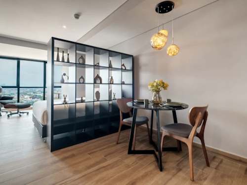 Open studio layout with dining table and bed tucked behind a stylish partition, flexible living in one bright space