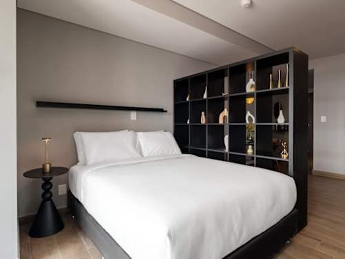 Restful king bed dressed in crisp white linens with smart shelving, a calm retreat after a day exploring Reforma