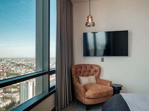 Cozy reading armchair by the window with a smart TV and sweeping city views over Reforma