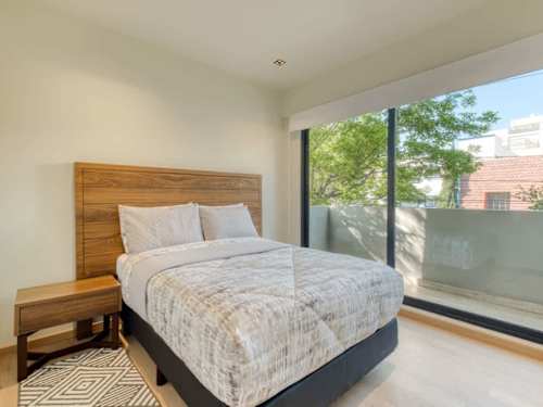 Restful bedroom with a comfy double bed and soft natural light through the balcony window for a great night's sleep