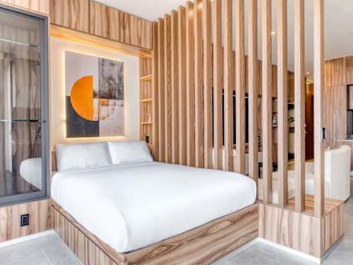 Restful bed dressed in crisp white linens behind wood-slat screens, serene nights near El Angel