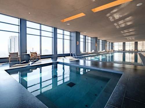 Indoor lap pool framed by tall windows, swim in comfort in the heart of the city