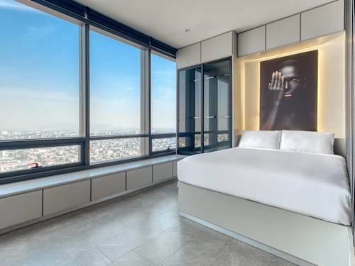 Bright bedroom with a crisp white bed and wide city windows, wake to the Reforma skyline