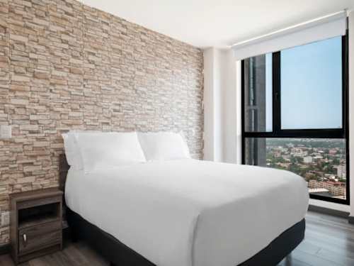Restful bedroom with a plush king bed and stone accent wall, wake to the Polanco skyline