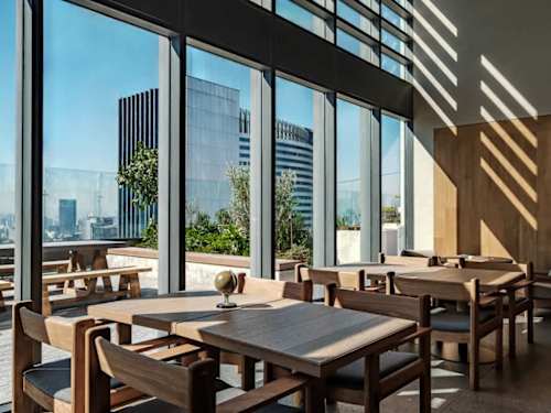 Sunlit dining set against floor-to-ceiling glass, meals with the city spread below