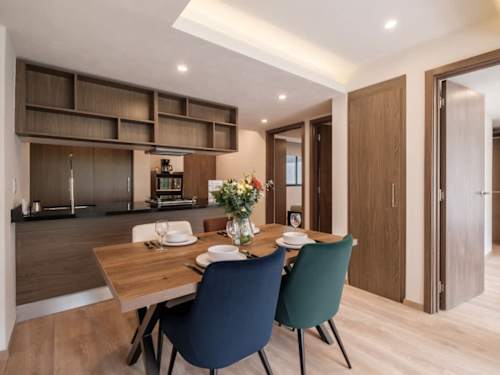 Sleek kitchen with wood cabinetry flowing into a bright dining nook, well-equipped and ready for home cooking