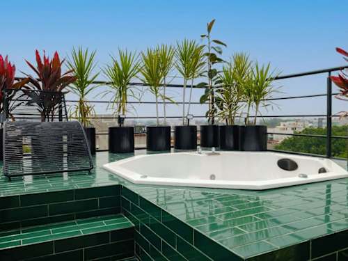 Emerald-tiled rooftop jacuzzi surrounded by planters and open sky, your private soak high above Roma Norte