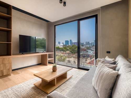Bright living room with a smart TV and low sofa beside big windows, relaxed downtime over the neighborhood rooftops