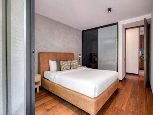 Serene bedroom with a wood-framed bed and soft linens, a calm place to rest after exploring the neighborhood