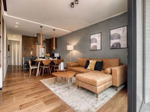 Open living and dining space with a tan leather sofa and warm wood floors, relaxed, design-led living in Roma Norte