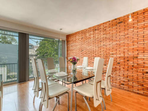 Elegant dining table for six against a warm exposed-brick wall, made for long, easy dinners at home