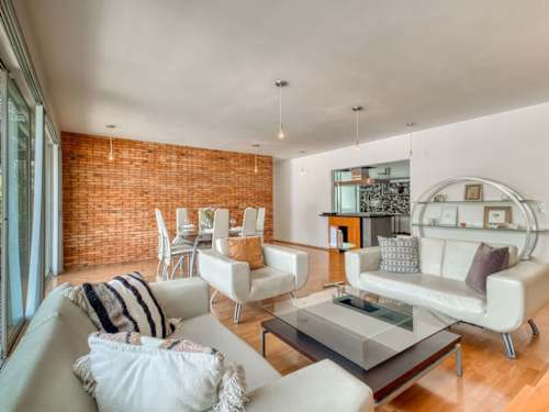 Bright open living room with comfy sofas and a glass coffee table, relaxed gathering space in Roma Norte