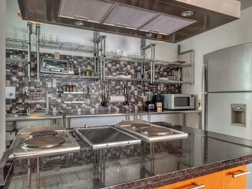 Statement industrial kitchen in gleaming stainless steel with full-size fridge, a real cook's setup