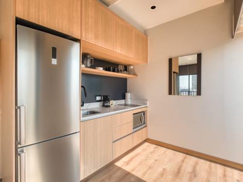 Compact modern kitchenette with stainless fridge and warm wood cabinets, easy meals in the city center