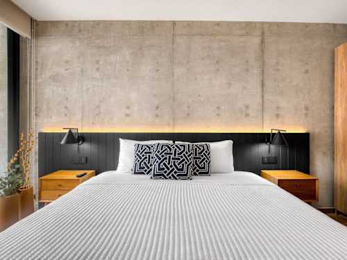 Serene king bedroom with a textured concrete wall and soft linens, a great night's sleep in the city