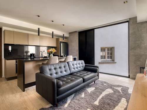 Comfortable lounge with a leather sofa and the kitchen just behind, effortless entertaining in Roma Norte