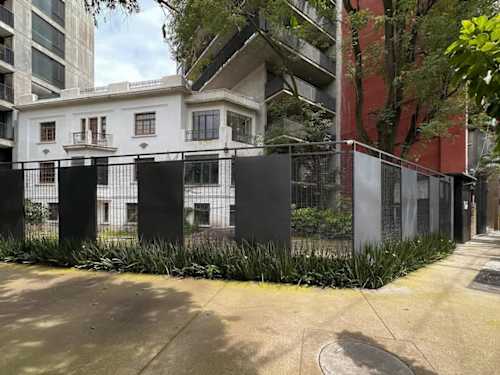Leafy gated building exterior on a quiet Roma Norte street, walkable to Parque Espana and countless cafes