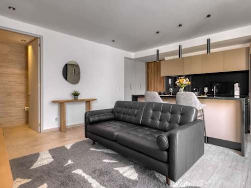 Bright living room with a handsome leather sofa opening to the kitchen, easy, open-plan living