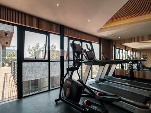 On-site gym with cardio machines by big windows, keep your routine without leaving the building