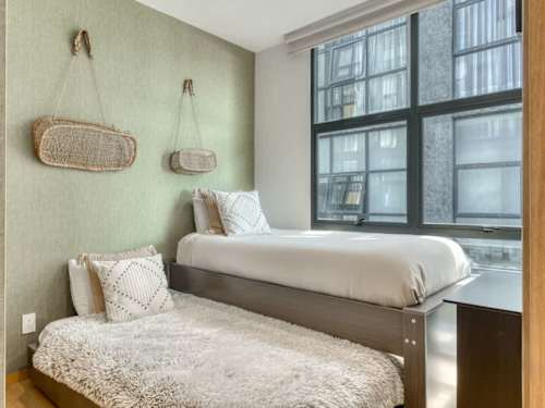 Cozy bedroom with a soft green accent wall and plush bed, a calm corner near Parque Mexico