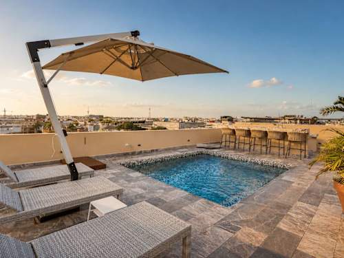 Shared rooftop pool with loungers and umbrellas