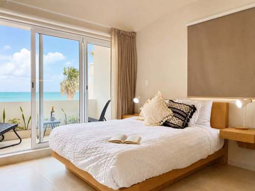 Restful bedroom with a comfy bed and sliding doors framing the water, wake up to bright Caribbean light