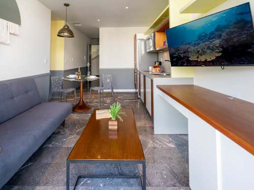 Bright living area with a comfy sofa and wall-mounted TV, easy relaxed evenings after a day at the beach