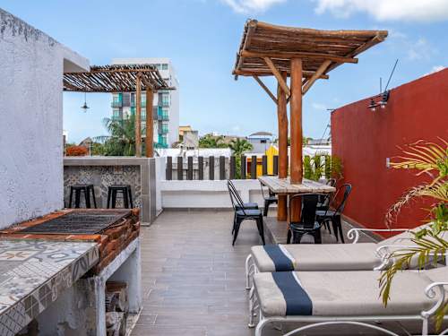 Cushioned loungers on the rooftop beneath the pergola, room to unwind under the Caribbean sky