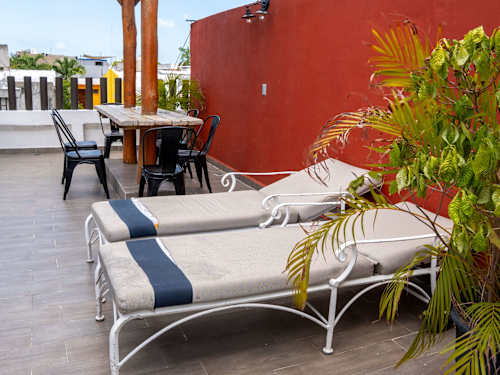 Rooftop loungers and bistro seating framed by a warm wall, a quiet escape above Cancun